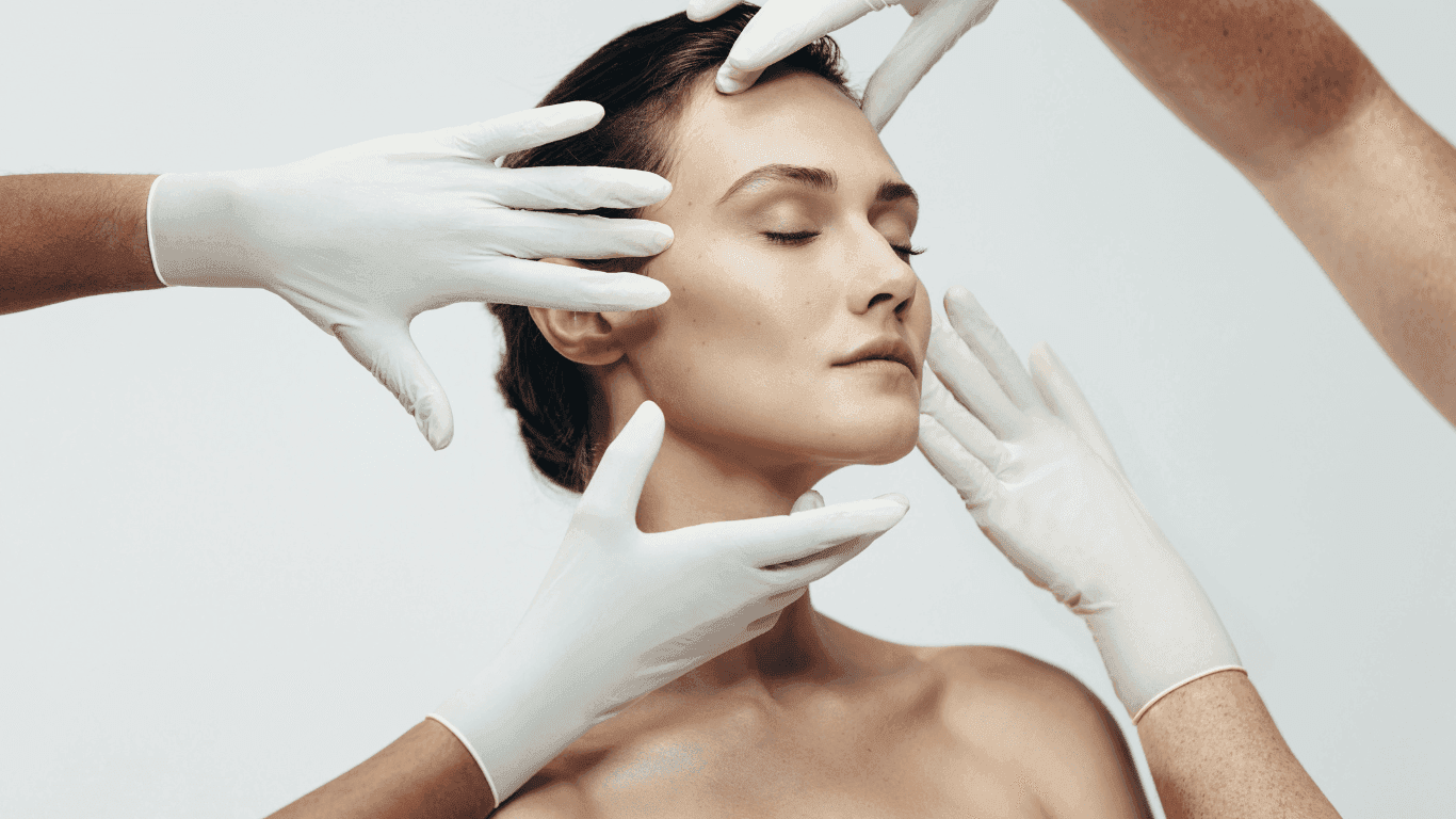 Person's face being examined by multiple hands wearing white gloves.