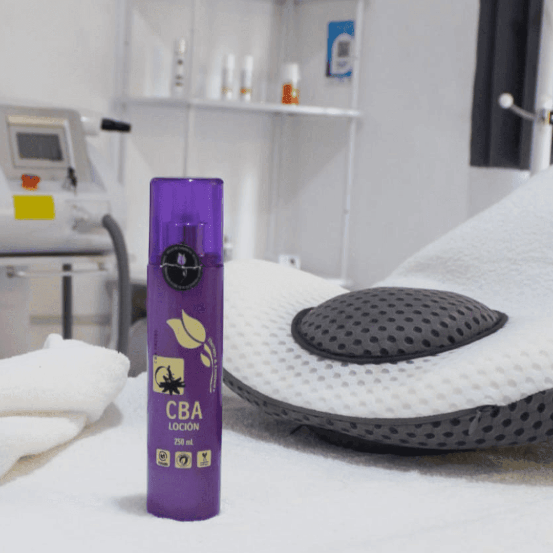 Purple bottle of CBA lotion on a table in a spa setting with equipment in the background.